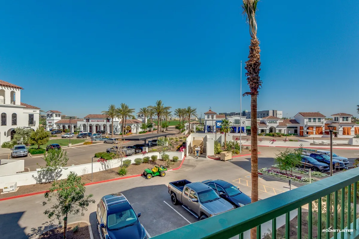 An exterior view showcasing palm trees, modern building architecture, a visible parking area, and a green vehicle. The scene is cheerful, with an inviting outdoor ambiance and easy access to the building from the parking area.