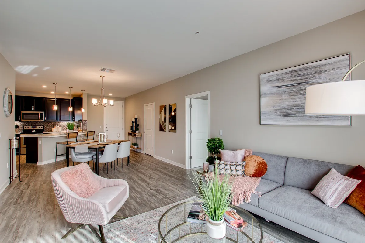 A bright, inviting space with a plush sofa, dining table, kitchen area, and colorful artwork. The arrangement allows for effortless flow between the kitchen, dining, and living areas, with ample light streaming in, enhancing the sense of openness.