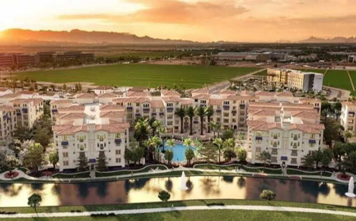 This exterior image captures the inviting swimming pool surrounded by landscaped gardens, with residential buildings in the background. The pool area features a peaceful fountain and is designed for both relaxation and social gatherings.